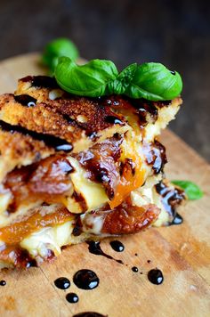 a grilled cheese and tomato sandwich on a cutting board with fresh basil sprigs