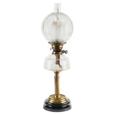 an old fashioned lamp with a glass globe on it's base and a metal stand