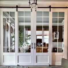 two white double doors with glass panels and a chandelier hanging from the ceiling