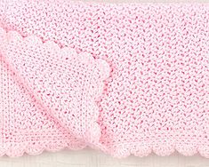 a pink crocheted blanket laying on top of a bed