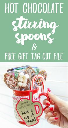 a person holding up a mug filled with candy and candies in front of the words hot chocolate fixing spoons and free gift tag cut file