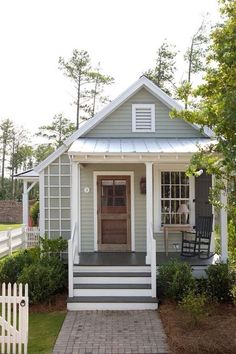 a small gray and white house with a porch, front door, and steps leading up to it