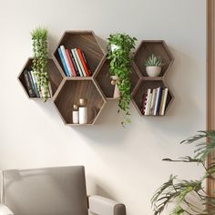 three wooden hexagonal shelves with books and plants on them against a white wall