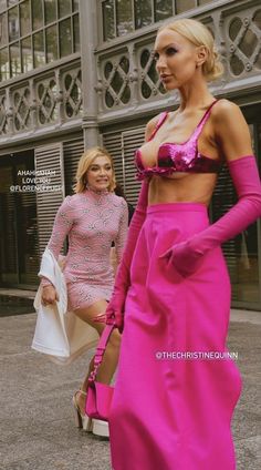 two women in pink outfits walking down the street