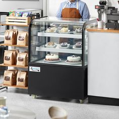 a man standing behind a display case filled with cakes