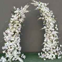 an arch made out of white flowers and greenery