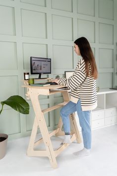 a woman sitting at a desk with a computer monitor and keyboard on top of it