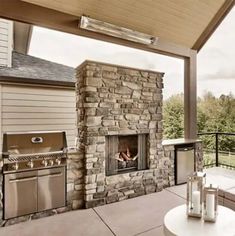 an outdoor kitchen with stone fireplace and grill