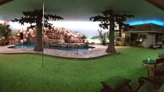 an indoor swimming pool with artificial grass and fake trees in the background at night time