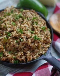 a skillet filled with rice and meat on top of a checkered table cloth