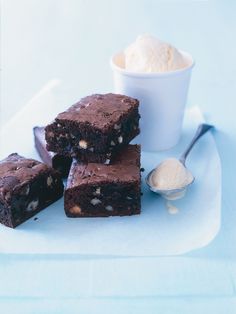 three pieces of brownie sitting on top of a white plate next to a scoop of ice cream