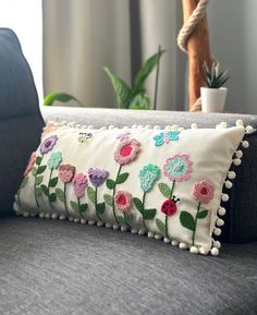 a pillow with flowers on it sitting on a couch next to a potted plant