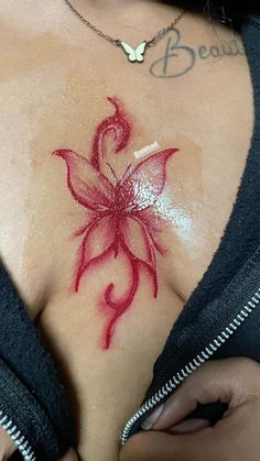 a woman with tattoos on her chest has a red flower painted on the side of her breast