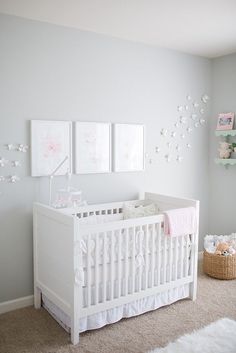 a white crib in a baby's room with two pictures on the wall