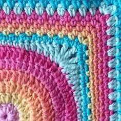 a crocheted rug with multicolored circles on it and a pink, blue, yellow, green, orange, and white design