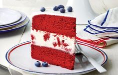 a slice of red velvet cake with white frosting and blueberries on top, sitting on a plate