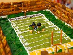 three birds are sitting on top of a football field cake that is decorated with grass and sticks