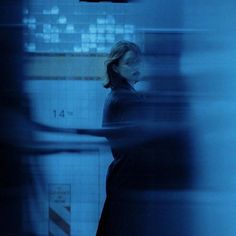 a blurry photo of a woman standing in a blue room with tiled walls and floor