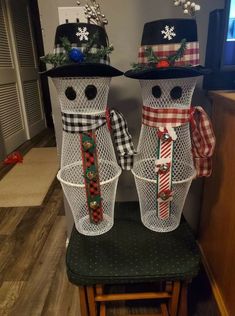 two snowmen made out of wire sitting on top of a chair