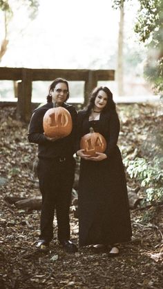 a man and woman holding carved pumpkins in their hands