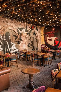 the interior of a restaurant with wooden tables and leather couches, decorated with lights