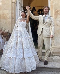 a man and woman in wedding attire standing on steps with their hands up to the sky