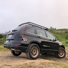 a black suv parked on top of a dirt road