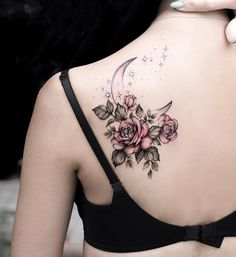 the back of a woman's shoulder with roses and a crescent tattoo on it