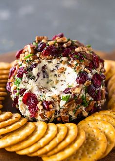 a cheese ball with cranberries and nuts on top of crackers