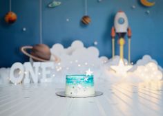 a small cake sitting on top of a table next to a wall with space decorations