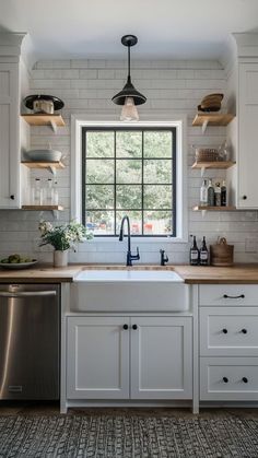 a kitchen with white cabinets and open shelving above the sink is seen in this image