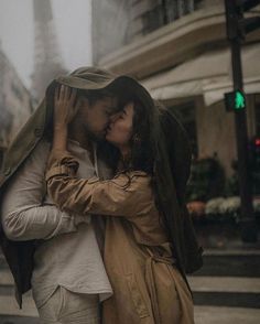 a man and woman kissing on the street in front of an eiffel tower