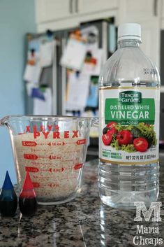 a bottle of vinegar next to a measuring cup with tomatoes and other ingredients on the counter