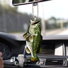 a fish shaped keychain hanging from the dashboard of a car