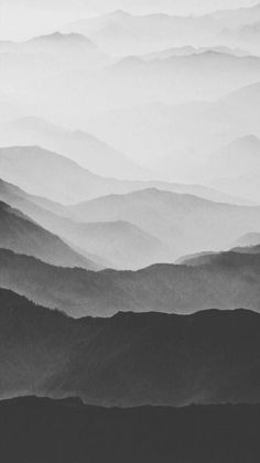 black and white photograph of mountains with fog in the air, taken from an airplane