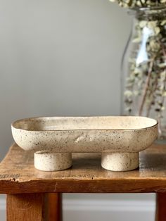 a bowl sitting on top of a wooden table next to a vase filled with flowers