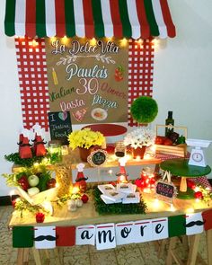 a table topped with lots of food under a red and white tent covered in lights