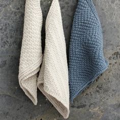 two blue and white knitted towels on a stone surface with one folded up in the middle