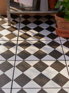 a black and white checkered floor with potted plants