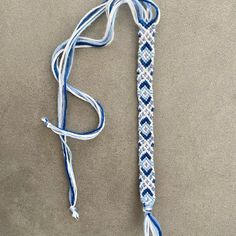 a blue and white lanyard with a knot at the end on a gray surface