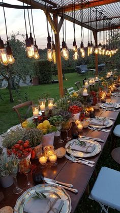 a long table is set up with plates and candles for an outdoor dinner or party