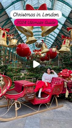 a woman sitting in a red and gold christmas sleigh with bells hanging from the ceiling