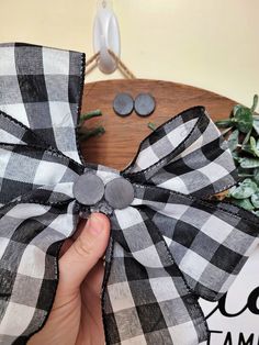 a person holding a black and white bow on top of a wooden table next to plants