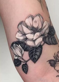 a black and white flower tattoo on the left arm, with leaves around it's edges