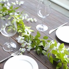 the table is set with plates, silverware and greenery on it for an elegant dinner