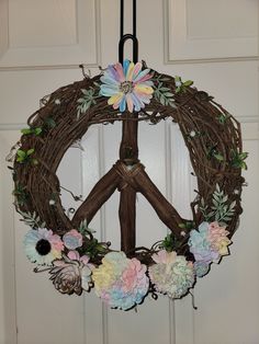 a peace sign made out of flowers hangs from a door hanger in front of a white door