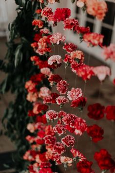 red and pink flowers are hanging from the ceiling