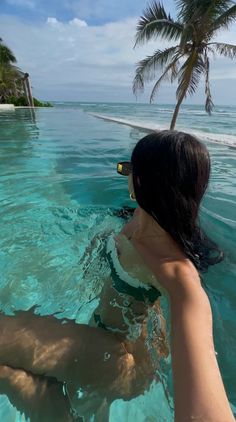 a woman swimming in the ocean with palm trees