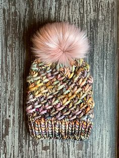 a knitted hat with a pink pom - pom on top of it