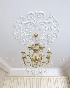 a chandelier hanging from the ceiling in a room with white walls and cabinets